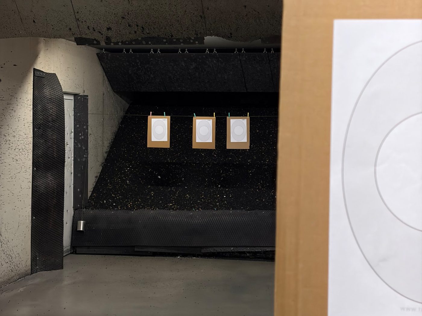 View down an indoor shooting lane with printed TargetVault targets hanging at the far end